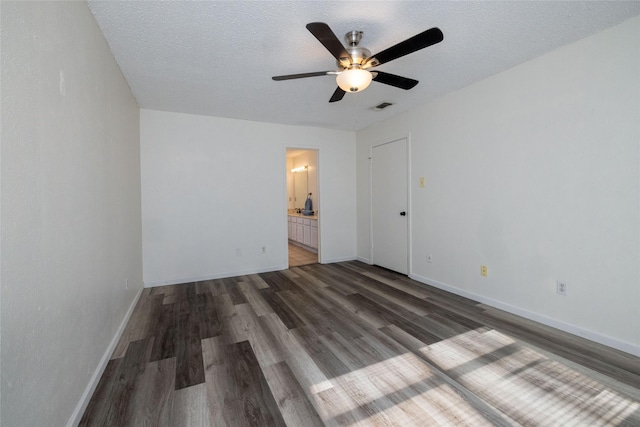 unfurnished bedroom featuring dark wood-style flooring, visible vents, a textured ceiling, and baseboards