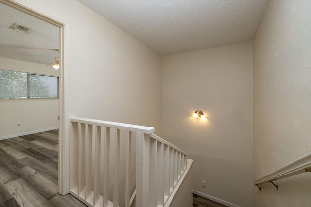 stairs featuring baseboards, visible vents, a ceiling fan, wood finished floors, and a textured ceiling