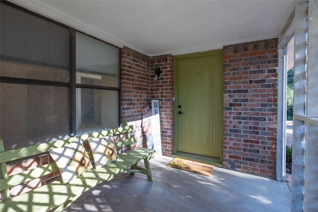 doorway to property with covered porch and brick siding