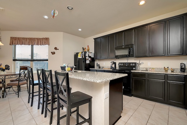 kitchen with light stone counters, light tile patterned floors, black appliances, and a kitchen island