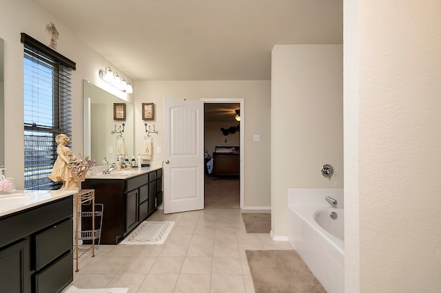 bathroom with tiled bath, vanity, and tile patterned flooring