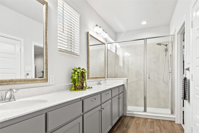 bathroom with a shower with door, hardwood / wood-style flooring, and double vanity