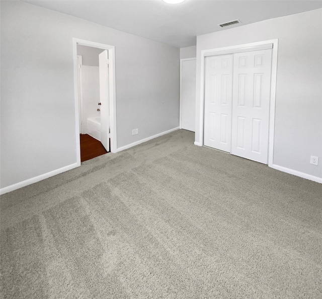 unfurnished bedroom featuring connected bathroom, carpet floors, and a closet