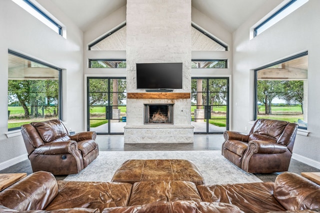 living room with a fireplace, high vaulted ceiling, a wealth of natural light, and concrete flooring