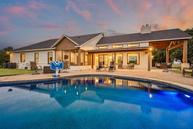 pool at dusk with central AC and a patio