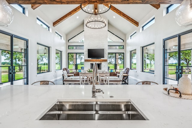 kitchen with high vaulted ceiling, beam ceiling, a fireplace, and sink