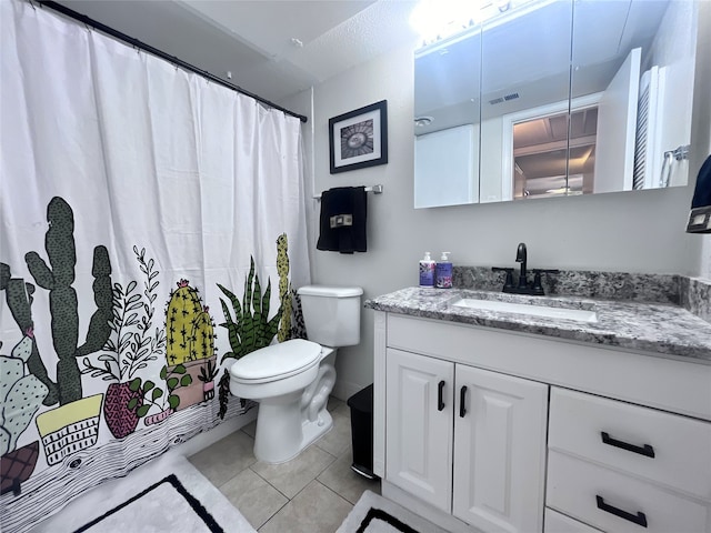 bathroom with toilet, vanity, and tile patterned floors