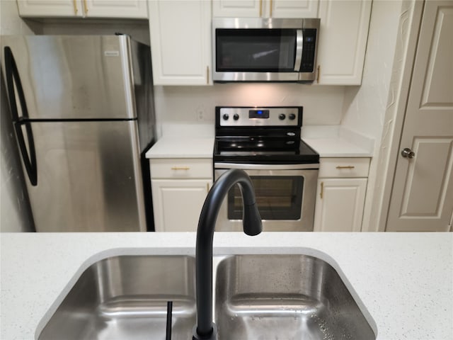 kitchen with appliances with stainless steel finishes, sink, and white cabinets