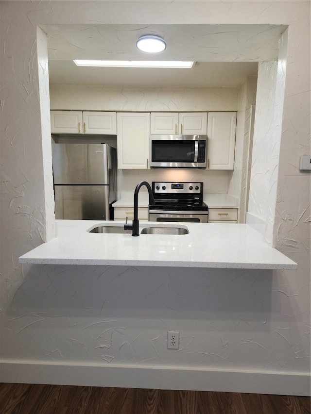 kitchen featuring appliances with stainless steel finishes, white cabinets, sink, and hardwood / wood-style flooring