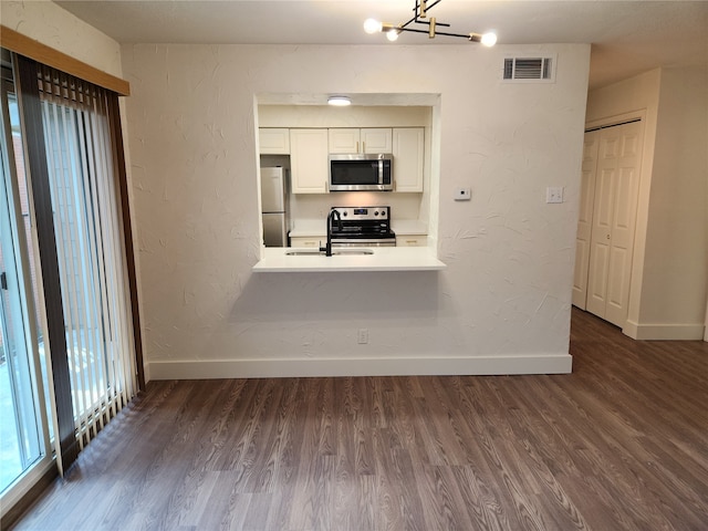 interior space with white cabinetry, dark wood-type flooring, an inviting chandelier, stainless steel appliances, and sink