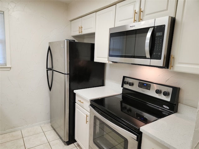 kitchen featuring light tile patterned floors, light stone countertops, stainless steel appliances, and white cabinetry