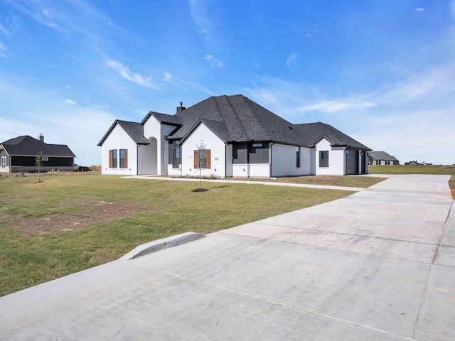 french country home featuring a garage and a front lawn