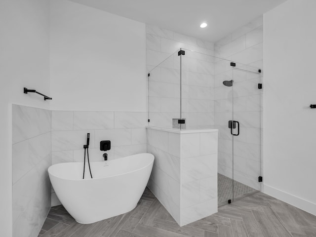 bathroom featuring tile walls and independent shower and bath