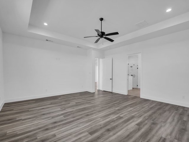 unfurnished room with hardwood / wood-style flooring, ceiling fan, and a tray ceiling