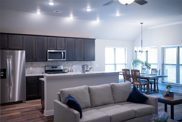 kitchen with dark hardwood / wood-style flooring, ceiling fan with notable chandelier, decorative backsplash, appliances with stainless steel finishes, and dark brown cabinetry