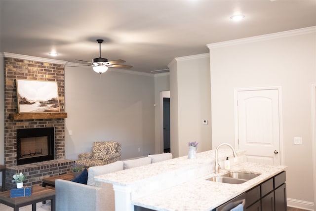 interior space with ceiling fan, crown molding, light stone countertops, a brick fireplace, and sink