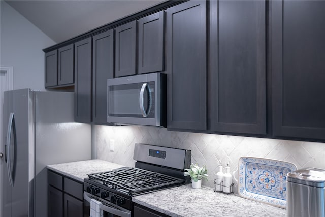 kitchen featuring light stone counters, backsplash, and stainless steel appliances