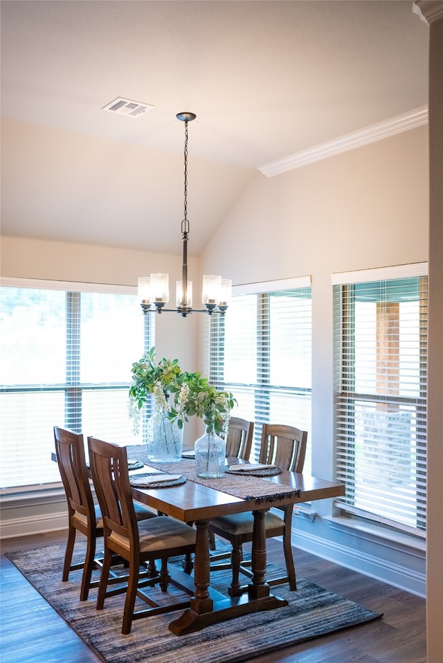 dining area with vaulted ceiling, an inviting chandelier, hardwood / wood-style flooring, and crown molding