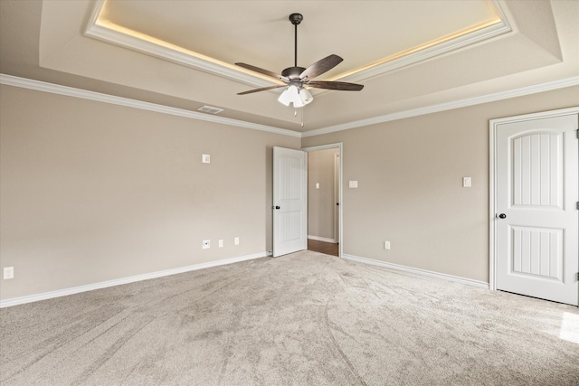 carpeted empty room with a tray ceiling, ceiling fan, and ornamental molding