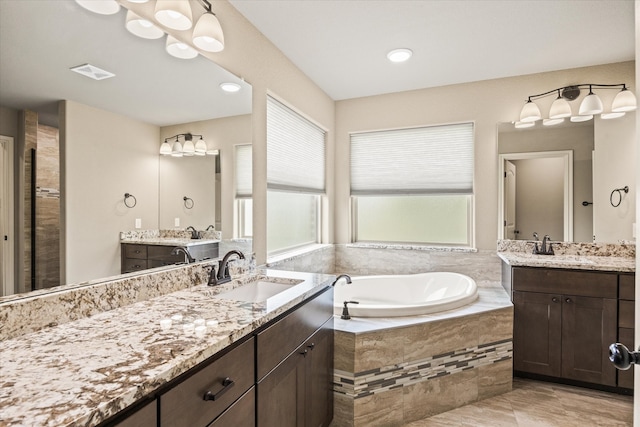 bathroom featuring vanity and a relaxing tiled tub