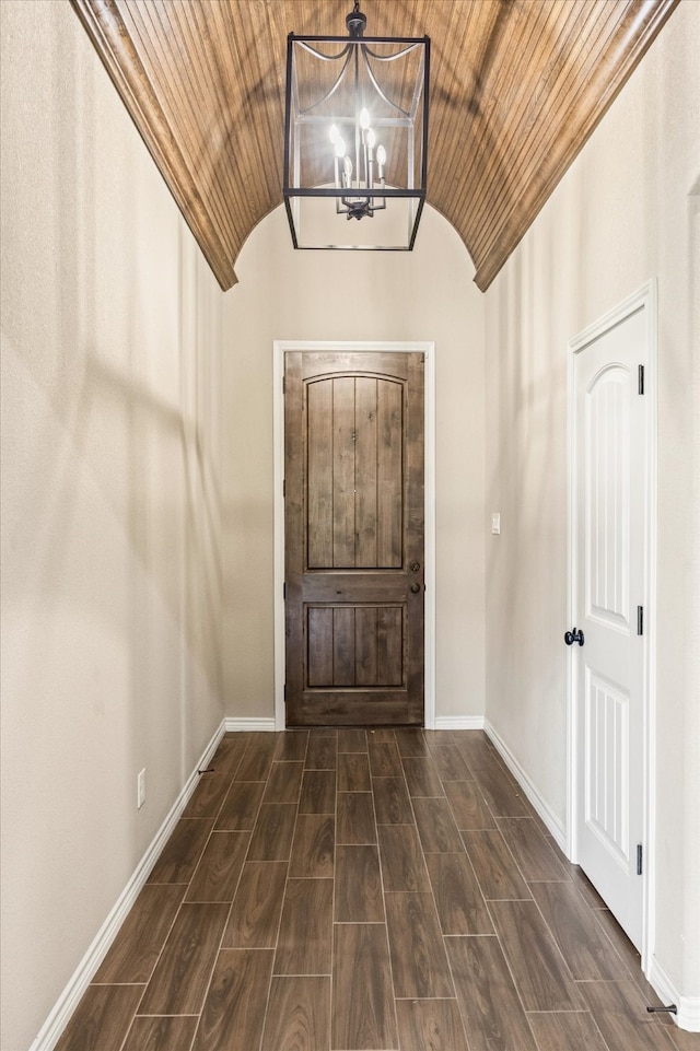 foyer entrance with wood ceiling, vaulted ceiling, a notable chandelier, and dark hardwood / wood-style floors