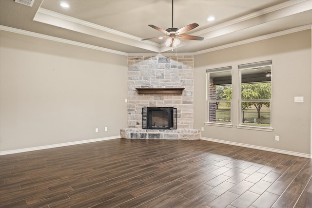 unfurnished living room featuring a raised ceiling, dark wood-type flooring, ceiling fan, and a stone fireplace