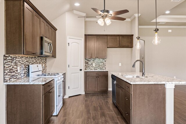 kitchen with appliances with stainless steel finishes, dark wood-type flooring, sink, ceiling fan, and light stone counters