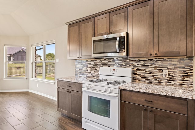 kitchen with lofted ceiling, light stone countertops, dark hardwood / wood-style floors, and white range with gas cooktop