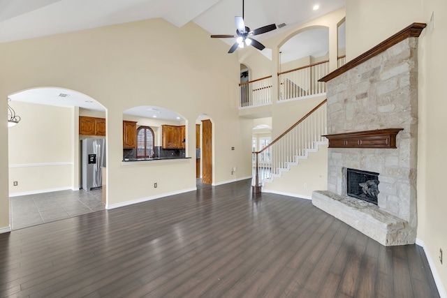 unfurnished living room with ceiling fan, high vaulted ceiling, hardwood / wood-style flooring, and a stone fireplace