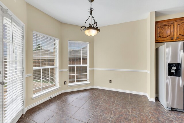 unfurnished dining area with plenty of natural light and dark tile patterned floors