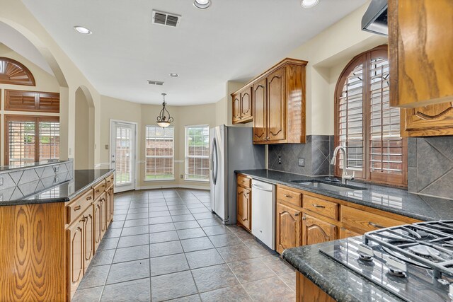 kitchen with backsplash, sink, white dishwasher, and plenty of natural light