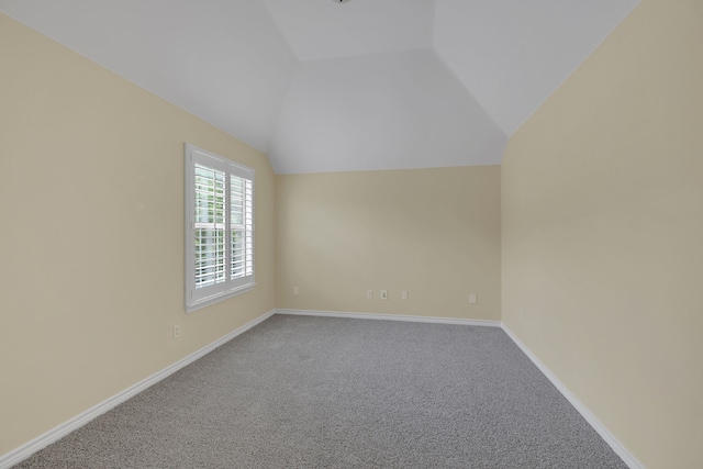 carpeted empty room featuring vaulted ceiling