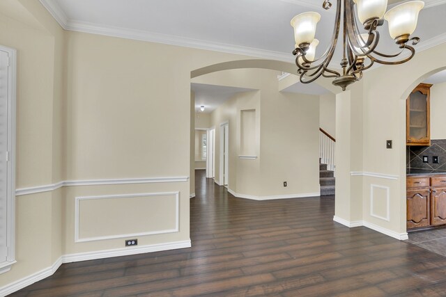 unfurnished dining area with dark hardwood / wood-style floors, an inviting chandelier, and crown molding