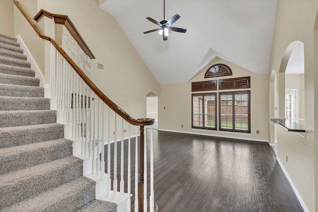 staircase with hardwood / wood-style flooring, ceiling fan, and high vaulted ceiling