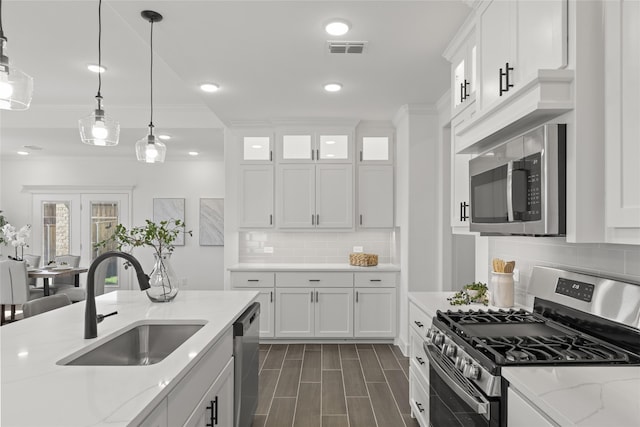 kitchen featuring white cabinetry, light stone countertops, pendant lighting, stainless steel appliances, and sink