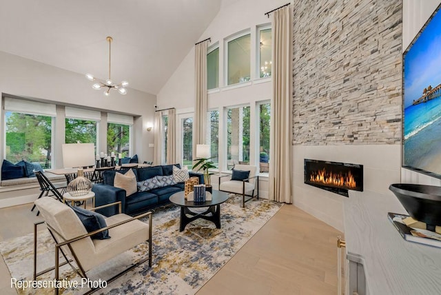 living room featuring a wealth of natural light, a fireplace, high vaulted ceiling, and a notable chandelier