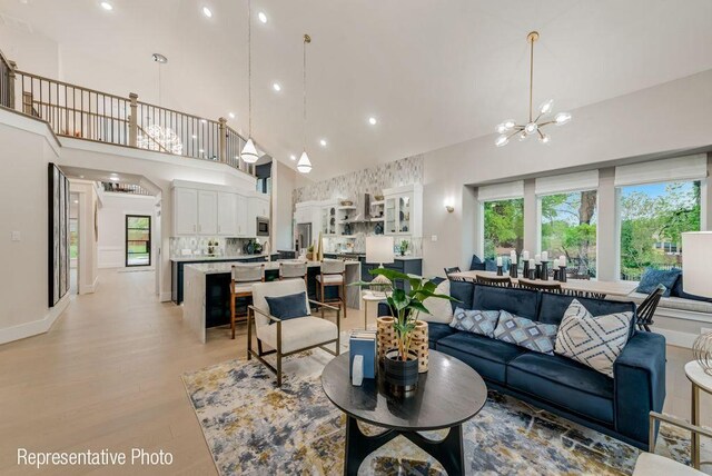 living room featuring a chandelier, a high ceiling, and light hardwood / wood-style floors