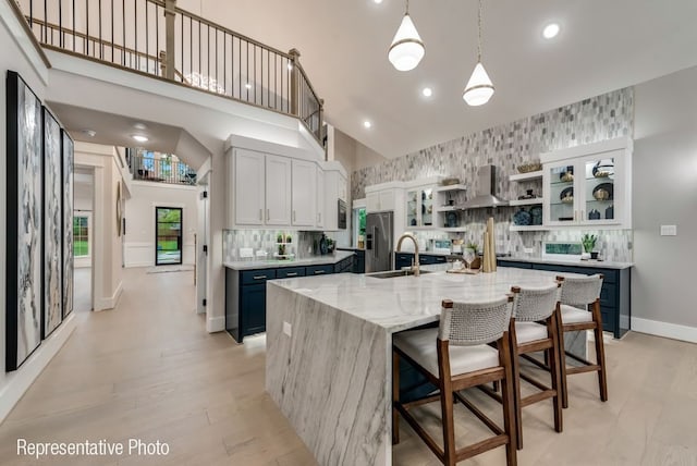 kitchen with exhaust hood, a kitchen breakfast bar, a towering ceiling, a large island, and stainless steel appliances