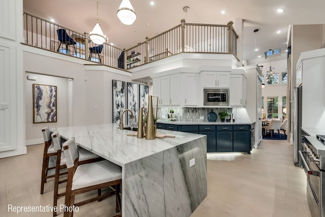 kitchen featuring pendant lighting, a high ceiling, blue cabinets, a large island, and stainless steel appliances