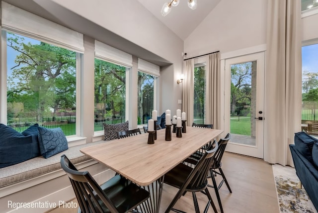 dining room with a chandelier, light wood-type flooring, and vaulted ceiling