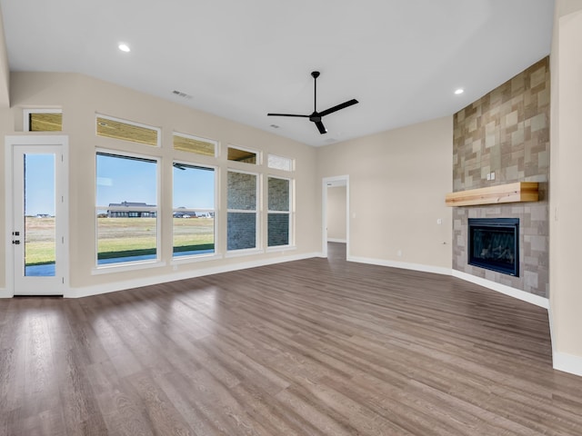 unfurnished living room featuring a tile fireplace, wood-type flooring, ceiling fan, and a healthy amount of sunlight