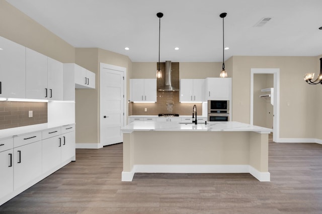 kitchen featuring a kitchen island with sink, white cabinets, sink, and wall chimney exhaust hood