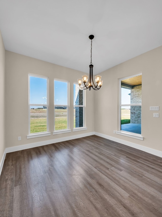 empty room featuring hardwood / wood-style flooring and an inviting chandelier