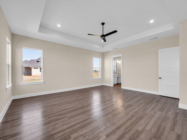 unfurnished room featuring ceiling fan, dark hardwood / wood-style floors, and a raised ceiling