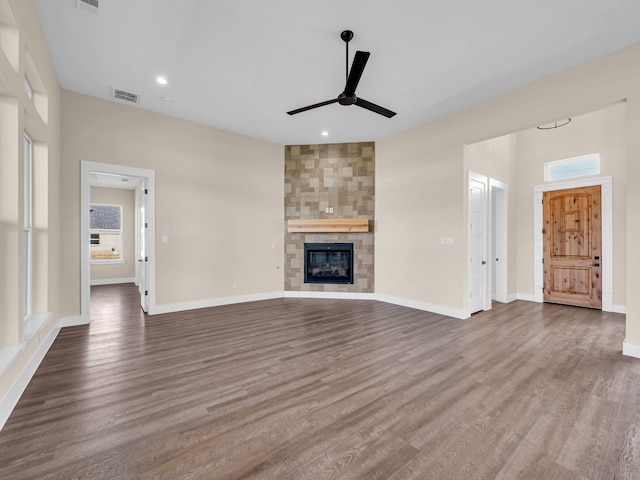 unfurnished living room featuring a tiled fireplace, hardwood / wood-style flooring, and ceiling fan