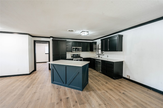 kitchen featuring light hardwood / wood-style flooring, a kitchen island, ornamental molding, stainless steel appliances, and sink