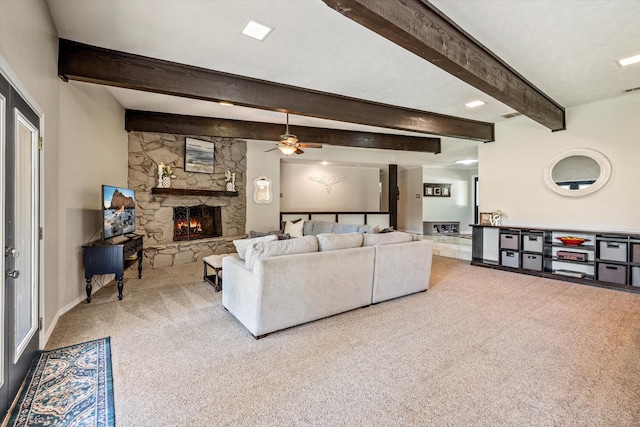 carpeted living room with beam ceiling, a stone fireplace, and ceiling fan