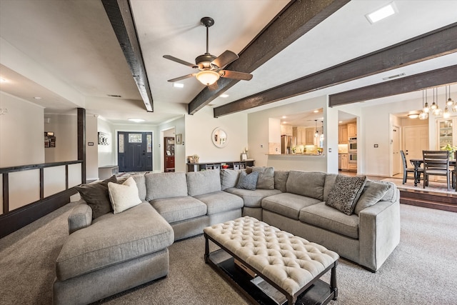 living room with ceiling fan with notable chandelier, beam ceiling, and carpet floors