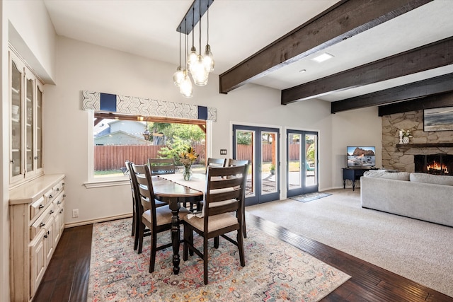 dining area with french doors, a fireplace, beam ceiling, and dark hardwood / wood-style floors