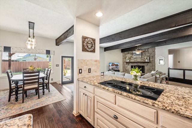 kitchen with beam ceiling, hanging light fixtures, a stone fireplace, dark hardwood / wood-style flooring, and black electric stovetop